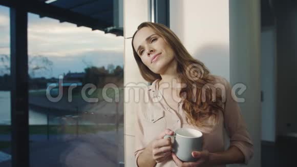 快乐的女人在工作一天后住在窗户附近放松的女人休息视频的预览图