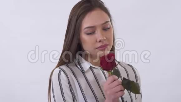 不高兴的年轻美女很伤心地从红玫瑰中拉起花瓣在画室里用白色拍摄视频的预览图