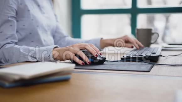 在笔记本电脑键盘和电脑鼠标上关闭女士手打字的镜头视频的预览图