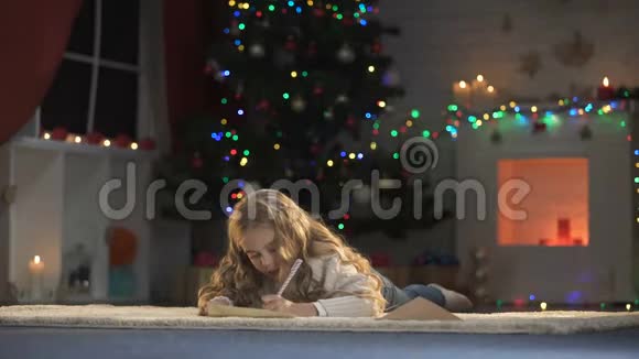 可爱的女孩把圣诞老人的信放进信封里幼稚地相信圣诞魔法视频的预览图