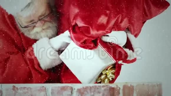 视频构图积雪覆盖圣诞老人把礼物扔进烟囱视频的预览图