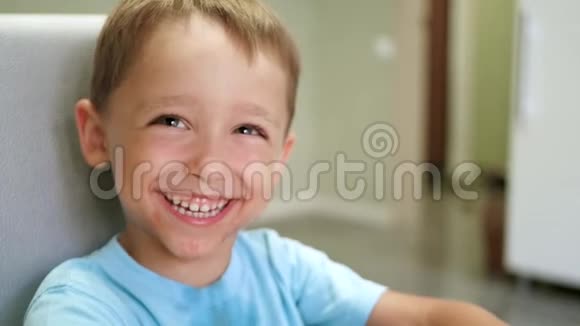 一个可爱的小孩子坐在厨房的桌子旁正吃着一个有食欲的多汁的西瓜会笑的家伙视频的预览图