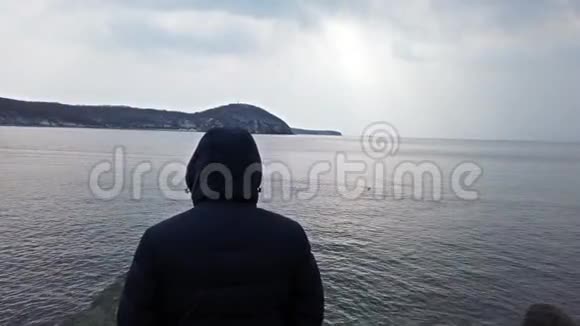 一个穿着蓝色夹克带着兜帽看海景的人海参崴普里莫斯基视频的预览图