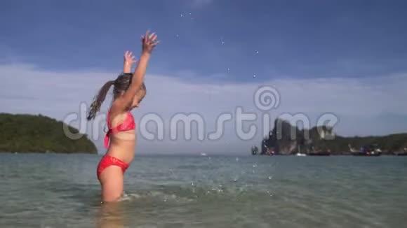 穿泳衣的小漂亮女孩在温暖的夏天的海洋里玩耍泼水视频的预览图