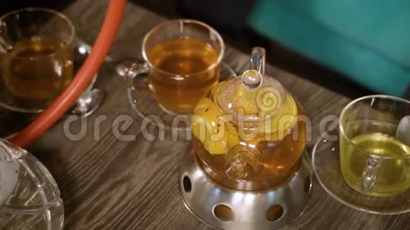 热的美味水果茶在茶壶和杯子在木桌上视频的预览图