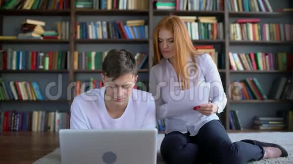 男女学生在图书馆学习和使用笔记本电脑两个学生一起讨论视频的预览图