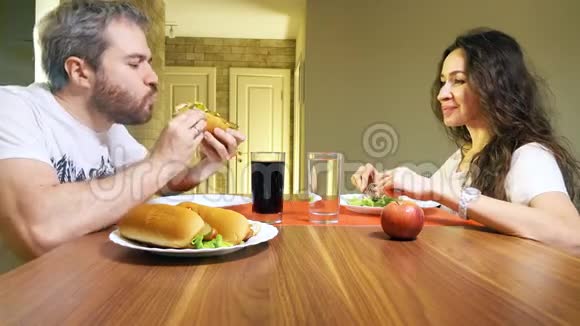 在家里吃热狗和生菜的白人男女视频的预览图