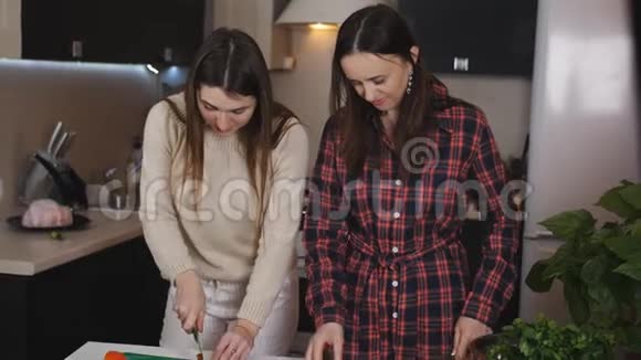 两个女孩正在厨房准备蔬菜沙拉女孩们把西红柿切成沙拉视频的预览图