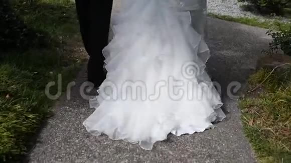 从腿上看新郎新娘正在散步一件漂亮的火车礼服视频的预览图