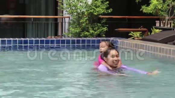 亚洲小女孩学习游泳从母亲在游泳池照顾暑假日视频的预览图