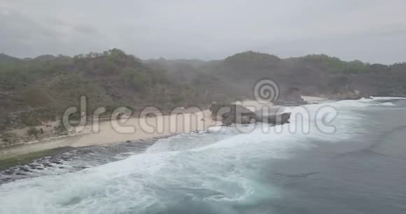 海浪拍打在小山下白色沙滩上的飞礁原始的画面未分级没有颜色原木视频的预览图