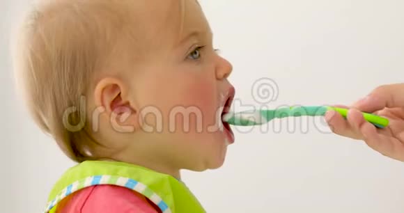 可爱的孩子用绿色勺子喂养视频的预览图