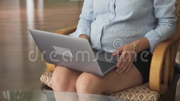 孕妇关上笔记本电脑从椅子上站起来视频的预览图