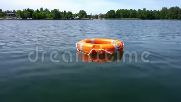 橙色的救生圈漂浮在远离海岸的湖水上万向节运动视频的预览图