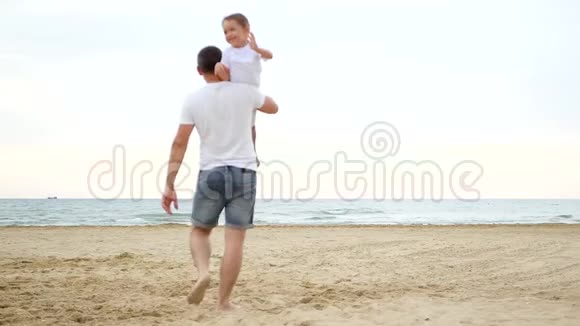 一个人扛着一个孩子走向大海一家人住在沙滩上小男孩笑了视频的预览图