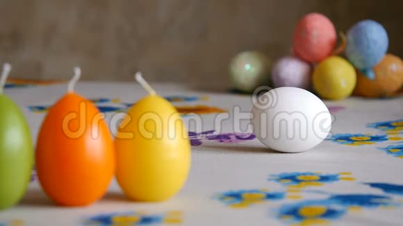 复活节雌性手在桌子上旋转白蛋背景中五颜六色的复活节彩蛋视频的预览图