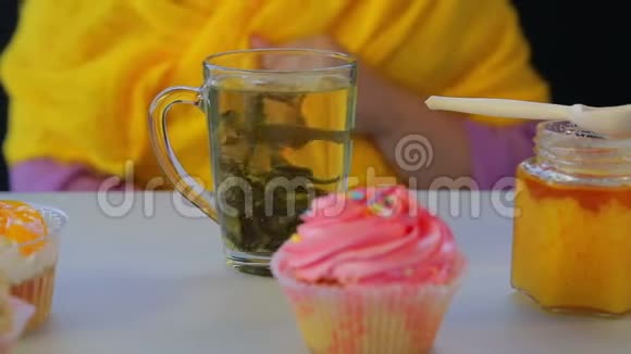 在一张灰色的桌子上用透明的杯子和蛋糕新鲜地冲泡绿茶视频的预览图
