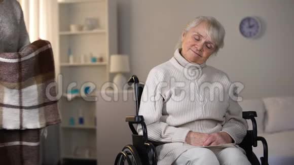 孙女用坐在轮椅上的格子花格子奶奶轻轻地盖着全家人视频的预览图