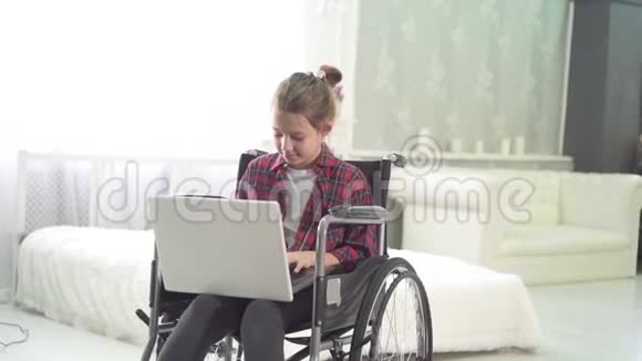 一个坐轮椅的少女的肖像在家里卧室里用笔记本电脑视频的预览图