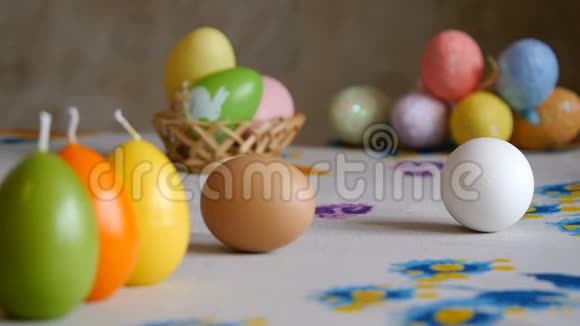 复活节快乐雌手从桌上取下两个复活节彩蛋五颜六色的蜡烛和彩蛋视频的预览图