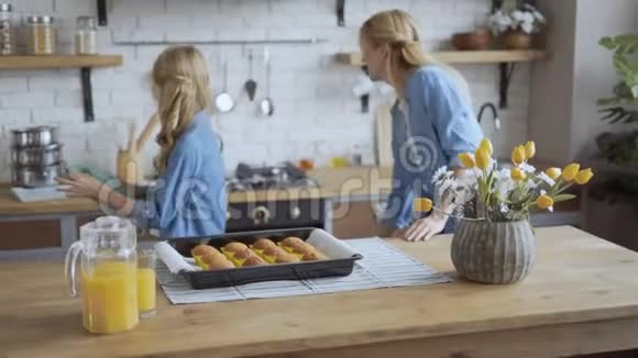 小女孩帮妈妈在厨房里烤饼干女孩从烤箱里拿出松饼用厨房的4K锅具视频的预览图