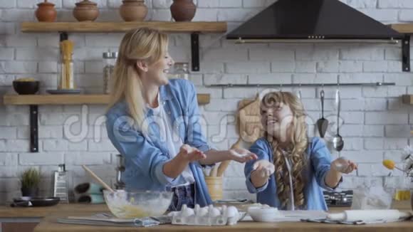 女人和女孩拍手面粉飞过厨房慢镜头拍摄幸福家庭观视频的预览图
