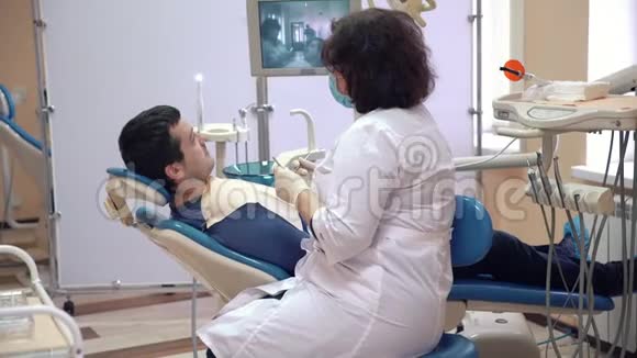 一名男性病人躺在诊所的牙科椅上接受牙医的咨询医生检查了视频的预览图