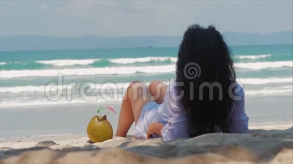 年轻的女人或快乐的女孩在海滩上晒日光浴享受海洋在阳光下喝椰子在阳光下放松视频的预览图