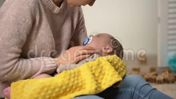 可爱的新生儿与假人躺在手臂女士拍打腹部减少绞痛视频的预览图