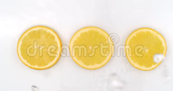 三个新鲜柠檬白色背景下流动的水的俯视图视频的预览图