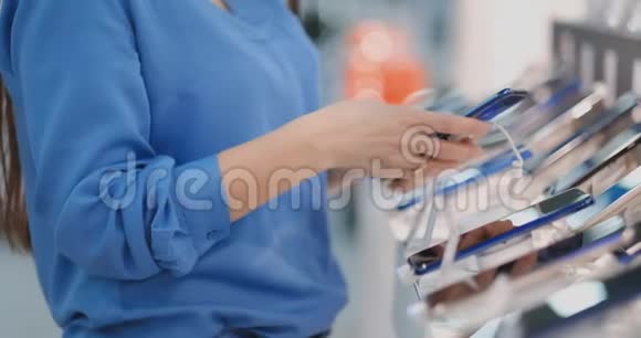在一家电子商店里一位拥有新智能手机选择的贴身女士在橱窗前购买视频的预览图