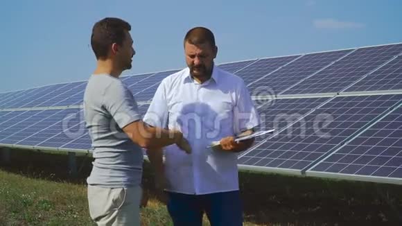 两个商人在太阳能电池的背景下握手视频的预览图