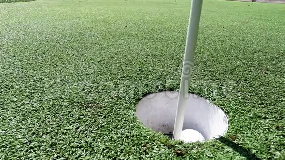白色高尔夫球击打旗棒在放绿色球时掉进洞里视频的预览图