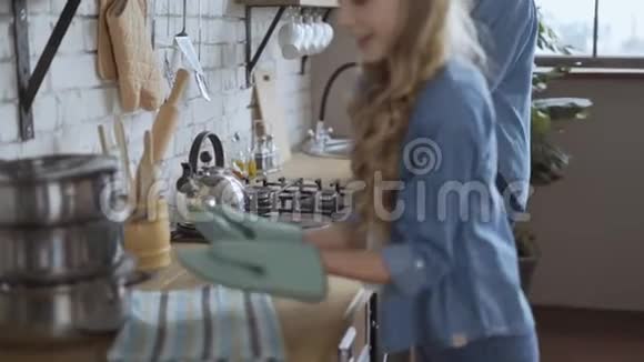 小女孩帮妈妈在厨房里烤饼干女孩从烤箱里拿出松饼用厨房的4K锅具视频的预览图