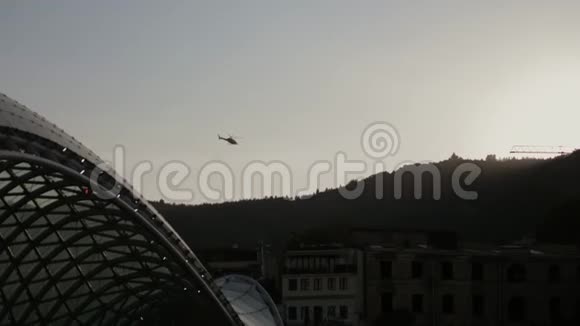 直升机的鼻子上挂着一架电影摄影机飞过城市上空并拍摄一部电影视频的预览图