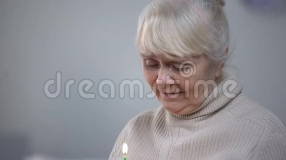 老年妇女在生日蛋糕上吹蜡烛老年孤独视频的预览图