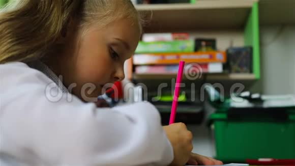 一个在书桌前穿校服的学生用粉红色铅笔写字视频的预览图