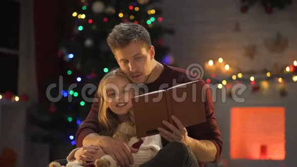 可爱的女孩子在闪闪发光的圣诞树旁的英俊男书视频的预览图