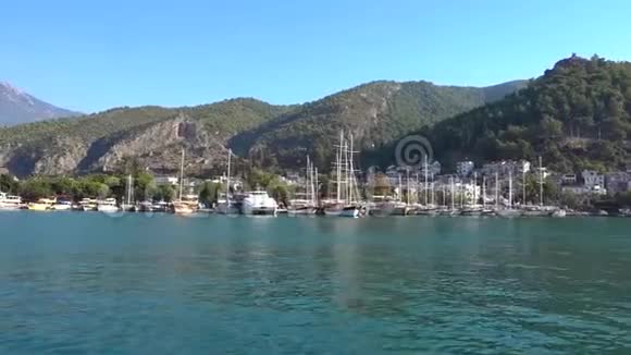 在美丽的山脉白色的房屋和蓝色的大海的背景下有游艇船只和船只的大型港口视频的预览图