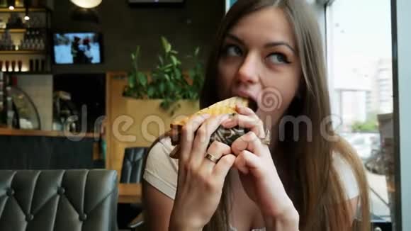 年轻饥饿的女人在咖啡馆里吃烤面包快餐店视频的预览图