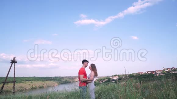 总计划美丽的男人和女人亲吻在框架的中心桥河树草房子靠岸视频的预览图