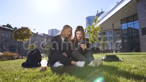 社交的白种人女朋友用平板电脑嘲笑平板电脑上的有趣照片坐在户外视频的预览图