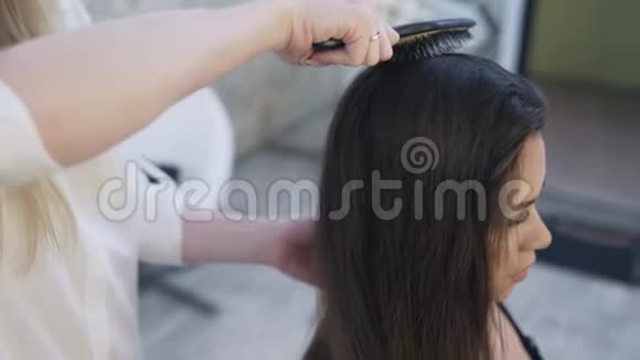 一位女理发师给一位客户梳长发并为他们做准备以便在视频的预览图