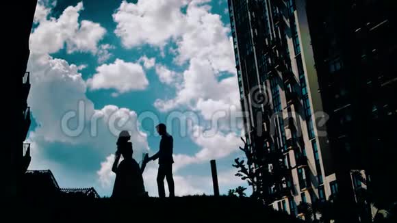 一个年轻人和一个女孩在美丽的天空上跳舞背景中令人惊叹的云两个情人在跳舞视频的预览图