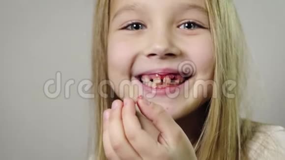 一个可爱的微笑女孩一个孩子她手里拿着一个撕裂的奶方和一个流血的牙龈下巴在一个房间里视频的预览图