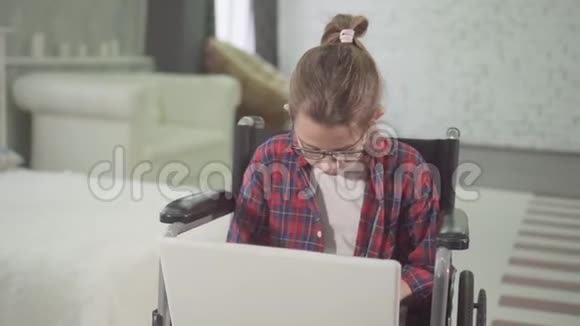 坐在轮椅上的残疾少女用笔记本电脑看着镜头微笑视频的预览图