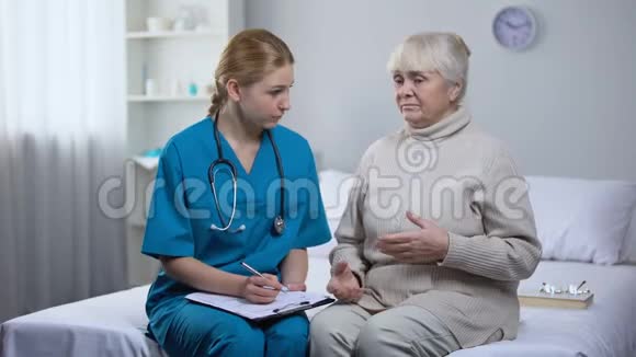 老年妇女抱怨医生头痛治疗师书写病历视频的预览图