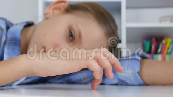 悲伤的孩子无聊的女孩在桌子上玩手指穿着不快乐的孩子不学习视频的预览图
