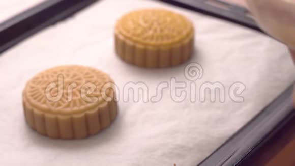 传统中秋节烤盘上用毛笔在粤式月饼糕点上涂抹鸡蛋视频的预览图