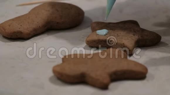 做圣诞姜饼特写镜头把蓝色奶油滴在饼干上视频的预览图